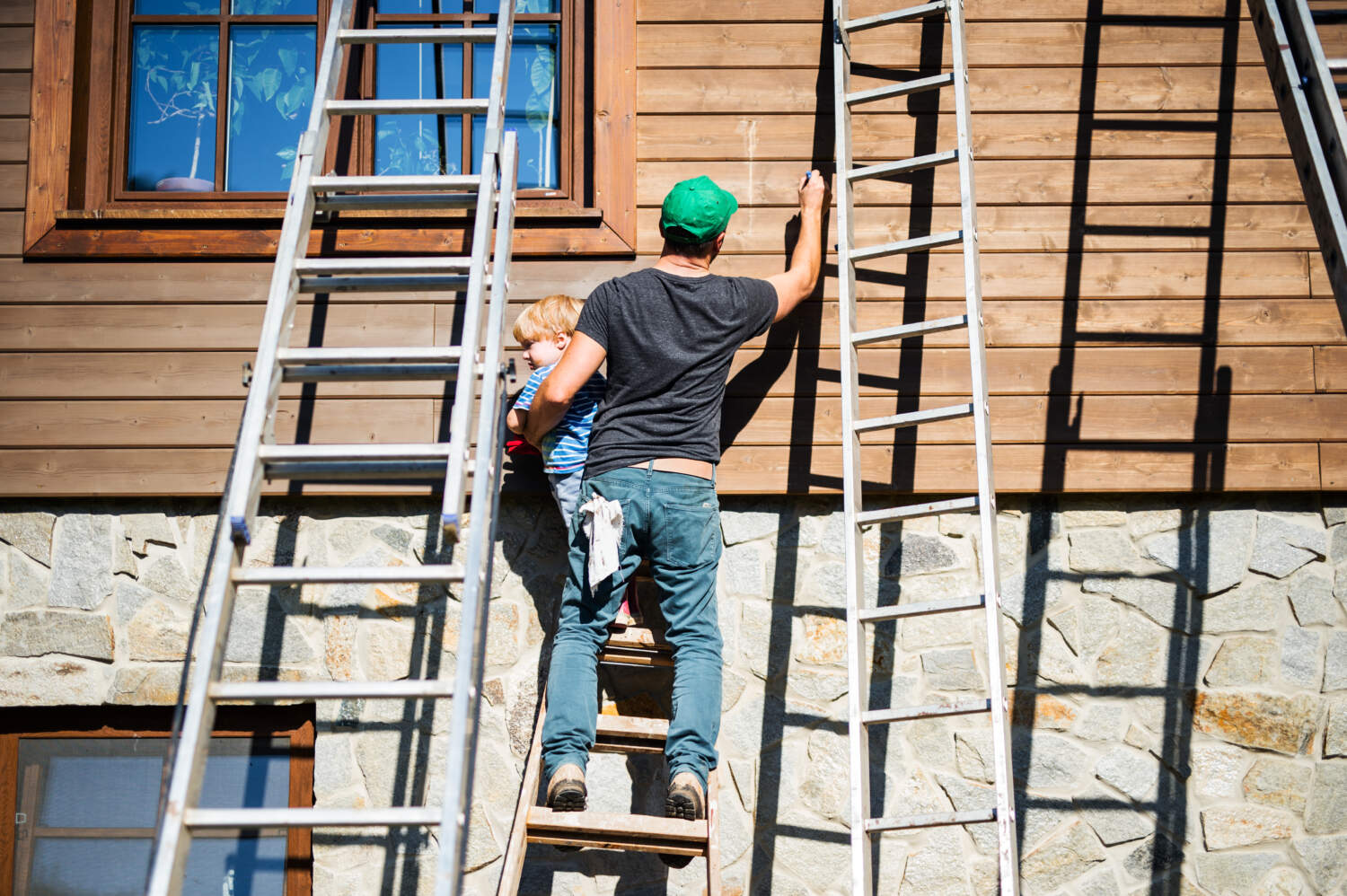 Photo d'un homme entrain de refaire la façade bois d'une maison