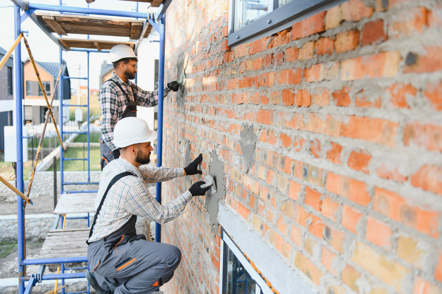Photo d'ouvrier entrain de rénover une façade de maison